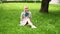 Woman sits in the park on the grass on a sunny day and thinks over a read book