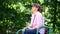 A woman sits in a Park and turns her face to the sun	.