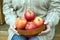 Woman sits on porch and holds bowl with apples close up