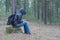 A woman sits on a stump in the woods early in the morning and ch