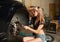 Woman sits on tire near car in auto repair shop