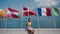 Woman sits under flying national flags of different countries, eats pizza, sunny