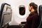 A woman sits at the window of an airplane at night