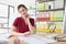 Woman sits at wooden table looking aside and pursing lips