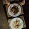 Woman sits at a wooden table in a restaurant and slices juicy steak