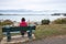 Woman sitting alon on a bench in a waterfront park