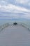 Woman sitting alone on bench at end of pier