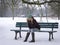 Woman sitting alone on park bench in winter