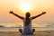 woman is sitting on beach at sunrise