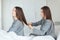 Woman sitting on bed and brushing her sistes twin hair