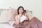 Woman sitting in bed watching the smartphone in the hand happily