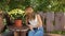 Woman sitting on a bench in the shade of the trees. woman smelling yellow flowers in pots