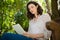 Woman sitting on bench and using digital tablet in garden on a sunny day