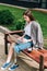 Woman sitting on bench and using laptop on street