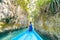 Woman sitting on boat in narrow canyon and turquoise lagoon at Bair Island, tropical paradise pristine coast rainforest blue sea.