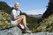 Woman Sitting On Boulder In Forest