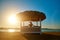 Woman sitting at Cabana with straw roof on a sandy beach on sunset