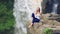 Woman sitting on a cliff next to Tegenungan Waterfall