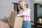 Woman sitting on couch at home opening carton box received parcel package