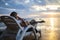 A woman is sitting on a deckchair on the seashore, having fun with her phone and enjoying the sunset