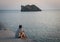 Woman sitting on dock looking at island