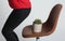 Woman sitting down onto chair with cactus against background, closeup. Hemorrhoids concept