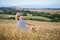 Woman sitting in dry barren grass, looking at camera