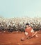 woman sitting in a field of cotton on red desert gravel in Arizona