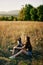 Woman sitting in a field with a dachshund dog smiling while spending time in nature with a friend dog in autumn at