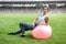 Woman sitting on fitball. Young and sportive woman training outdoors