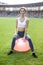 Woman sitting on fitball. Young and sportive woman training outdoors