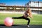 Woman sitting on fitball. Young and sportive woman training outdoors