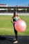 Woman sitting on fitball. Young and sportive woman training outdoors