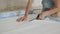 A woman sitting on the floor cuts off wallpaper with scissors for their subsequent pasting on the walls.