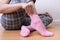 A woman sitting on the floor and putting on pink cozy cotton socks on her feet, warming legs and body in autumn and