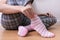 A woman sitting on the floor and putting on pink and white striped cozy cotton socks on her feet, warming legs and body