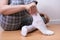 A woman sitting on the floor and putting on white cozy cotton socks on her feet, warming legs and body in autumn and