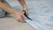 A woman sitting on the floor with scissors cuts off the blue wallpaper for the children's room.