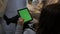 Woman sitting on the floor and using vertical tablet computer with green screen. Close up shot of woman`s hands with pad