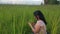 A woman is sitting in the green grass and working on a tablet in the park among the plan.