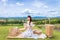 Woman sitting happily holding flowers with beautiful mountain sky view and woven basket on floor