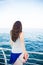 Woman sitting at the harbour on the quay with her back to the camera looking out at moored boats, shallow dof