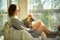 Woman sitting at home in a chair by the window stroking cat on her laps