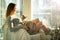 Woman sitting at home in a chair by the window stroking cat on her laps