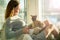 Woman sitting at home in a chair by the window stroking cat on her laps
