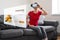 WOman sitting at home on the sofa with vr glasses buying grocery fruit food products.