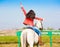 Woman sitting horse. Day. Half height. Red leather jacket. Back