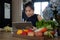 Woman sitting at kitchen table full of fresh vegetables and searching recipes on digital tablet