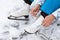 Woman sitting on lake ice, wearing figure skates and ties shoelaces with hands, close up-view