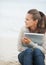 Woman sitting on lonely beach and embracing laptop